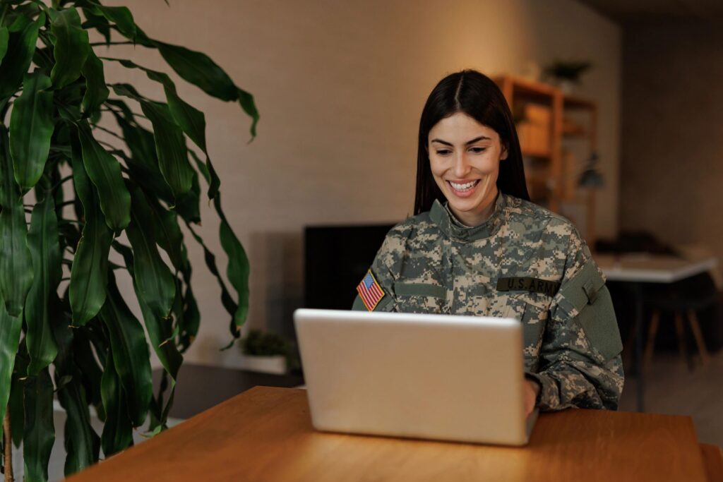 Smiling US Army soldier using laptop at home